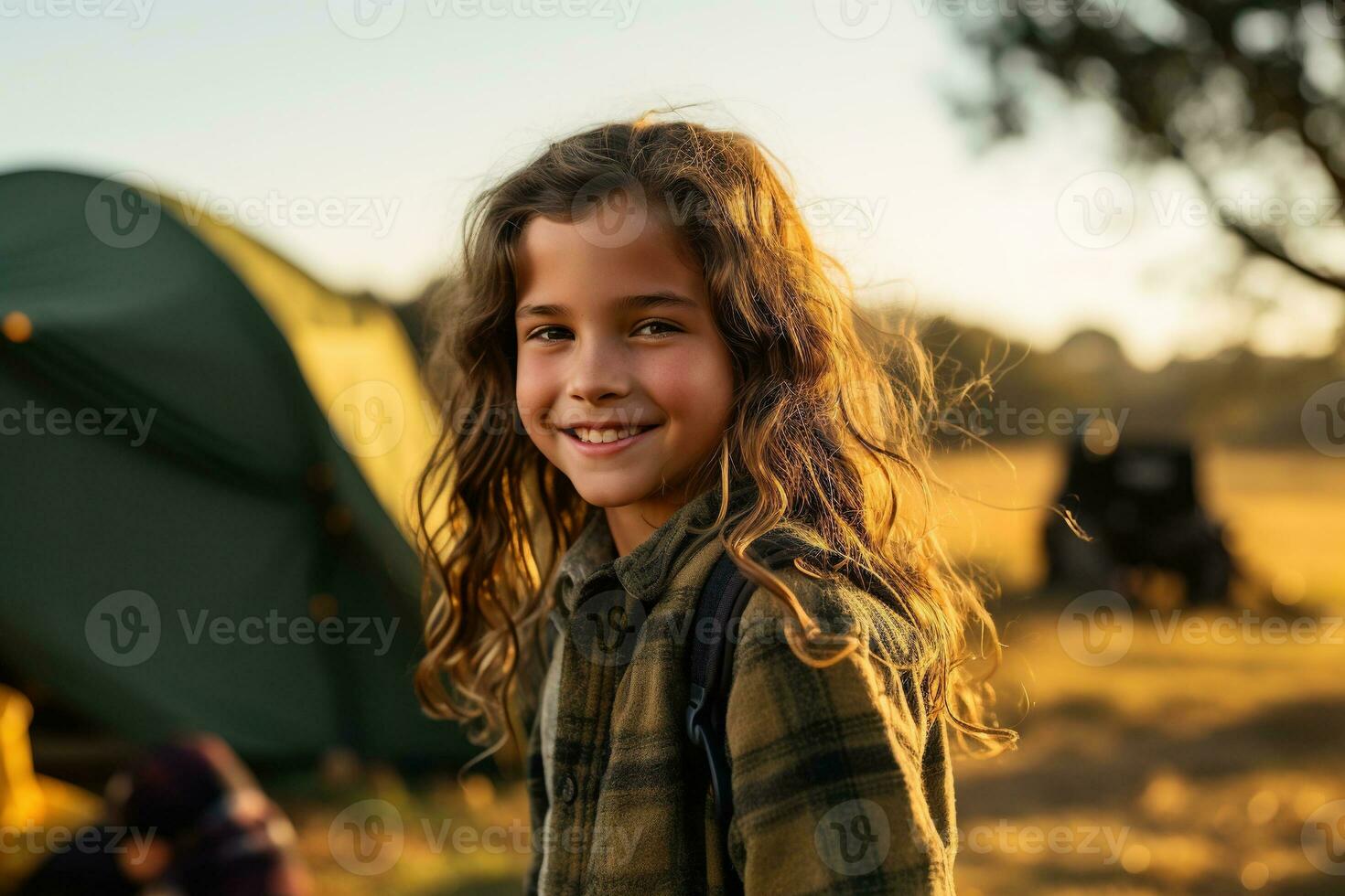 Portrait of cute little girl at camera while standing near camping tent at sunset AI generated photo