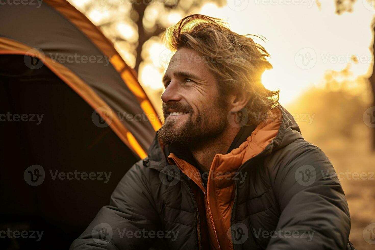 Portrait of man looking at camera while near camping tent at sunset AI generated photo
