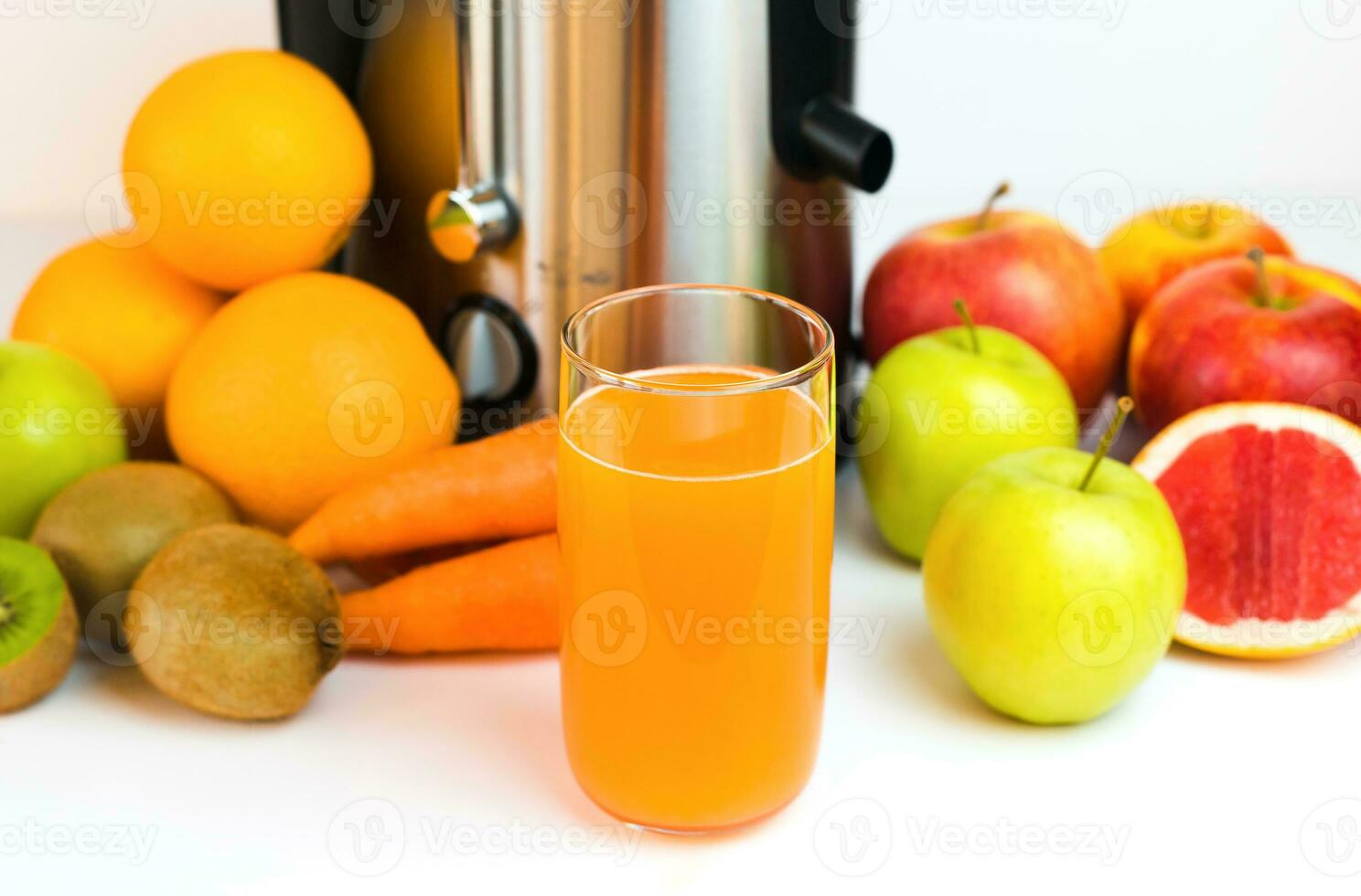 un vaso de recién exprimido Fruta jugo, Fruta y un moderno exprimidor en el mesa en el cocina. hecho en casa sano Fruta y vegetal jugos selectivo enfocar. de cerca. foto