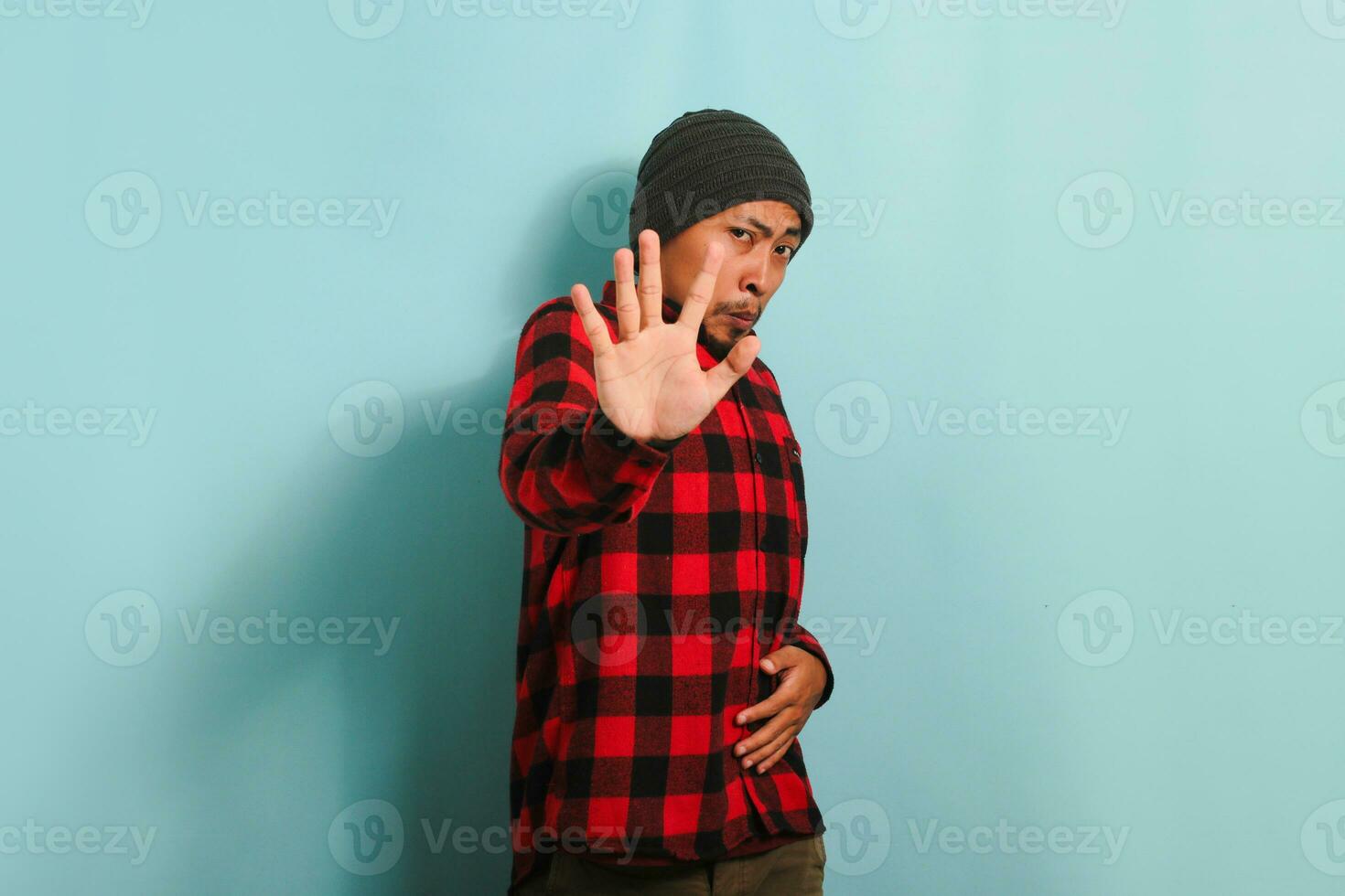 Annoyed young Asian man repulsing something with disgusted expression, isolated on blue background photo