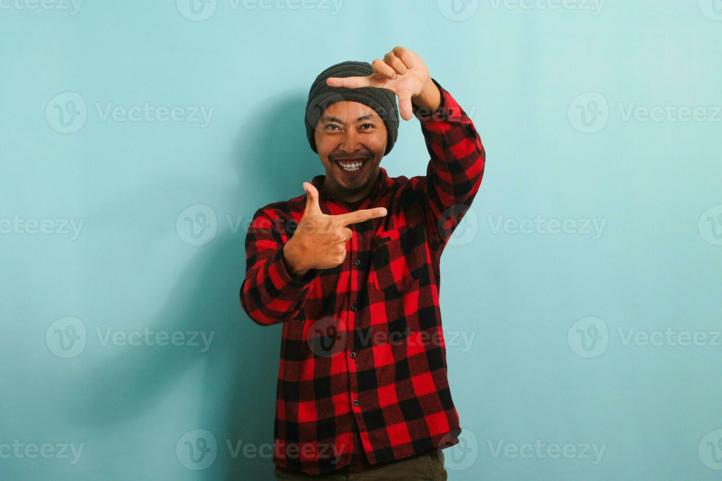 Excited Young Asian man is making a picture frame gesture, isolated on a blue background photo