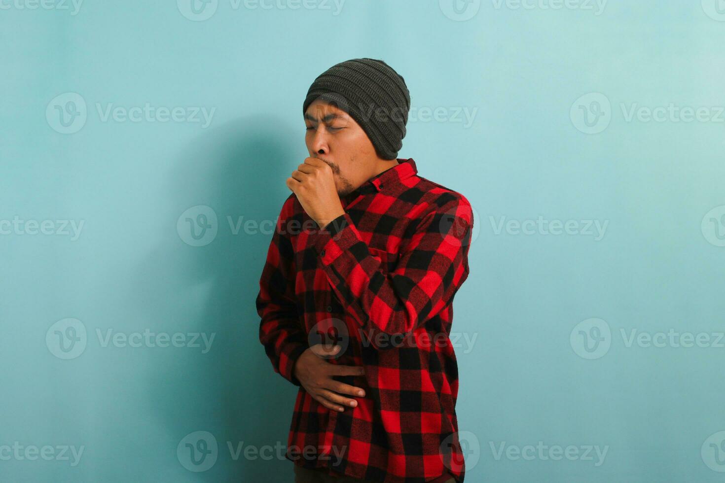 enfermo joven asiático hombre es tos y estornudos, sufrimiento desde un tos, gripe, aislado en azul fondo foto