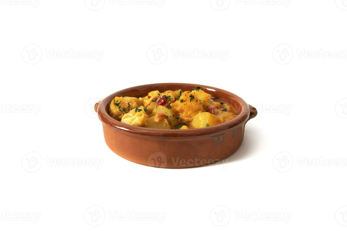 Potato stew with cod, served in a clay bowl. Isolated on white background. Spanish food concept. photo