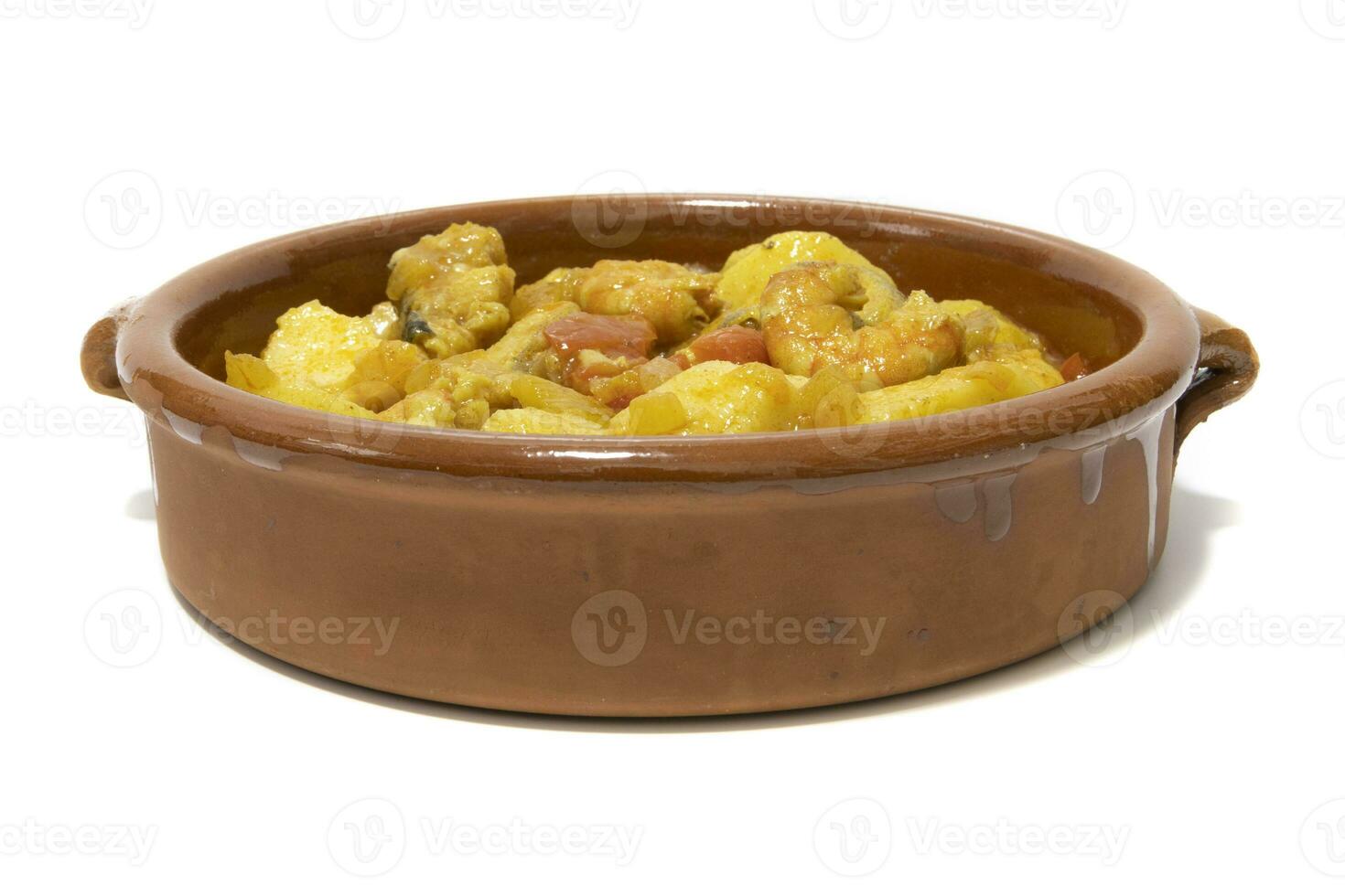 Potato stew with cod, served in a clay bowl. Isolated on white background. Spanish food concept. photo