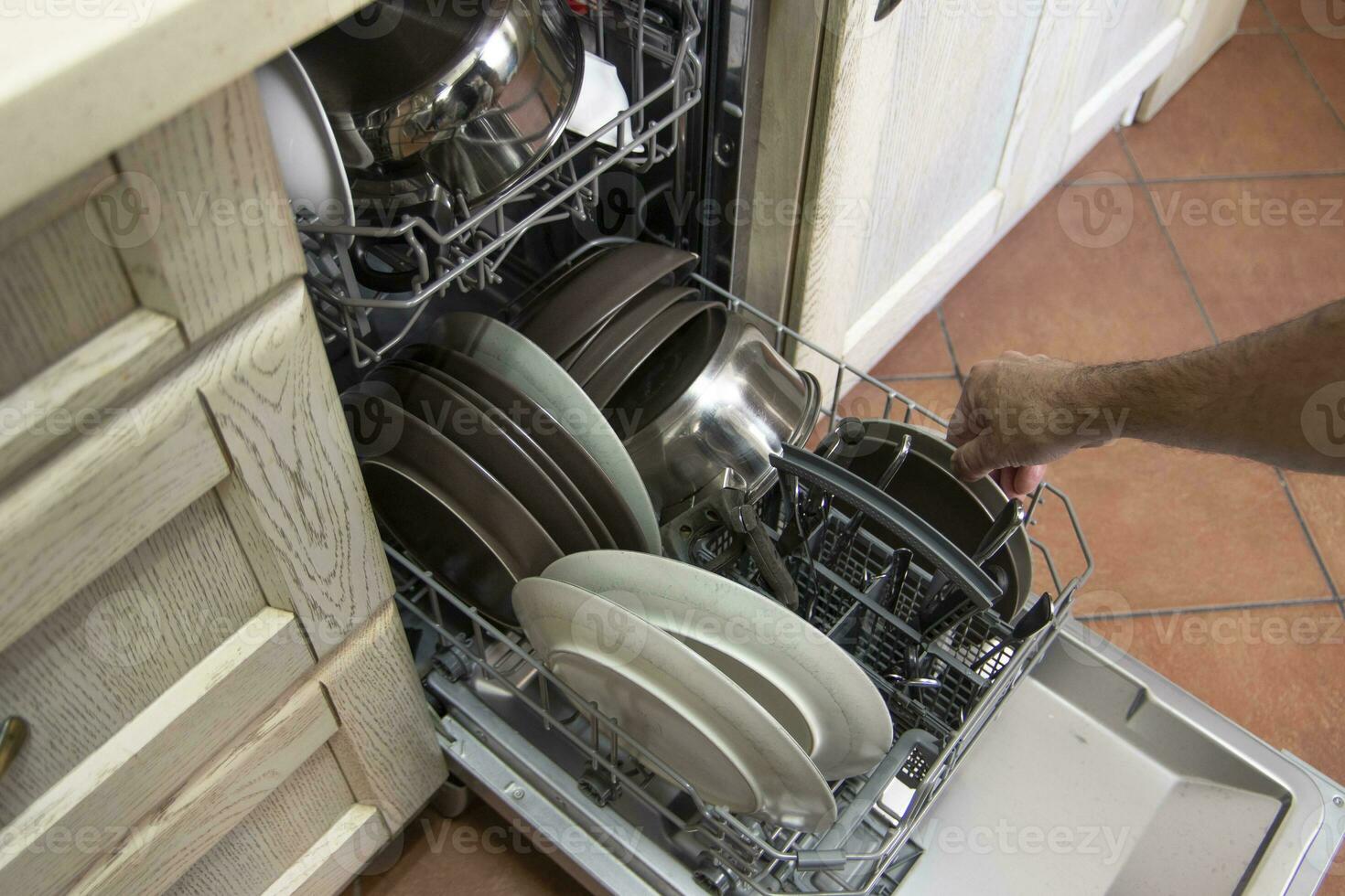 A man taking dishes out of a dishwasher. Concept of living single. photo