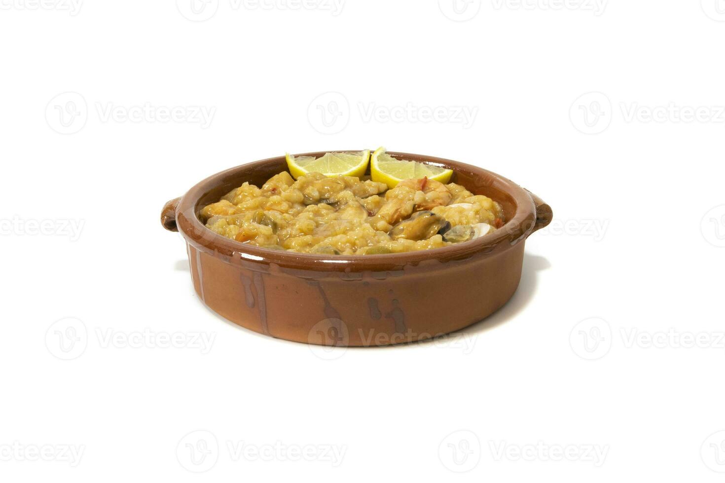 Rice with seafood, served in a clay bowl. Isolated on white background. Spanish food concept. photo