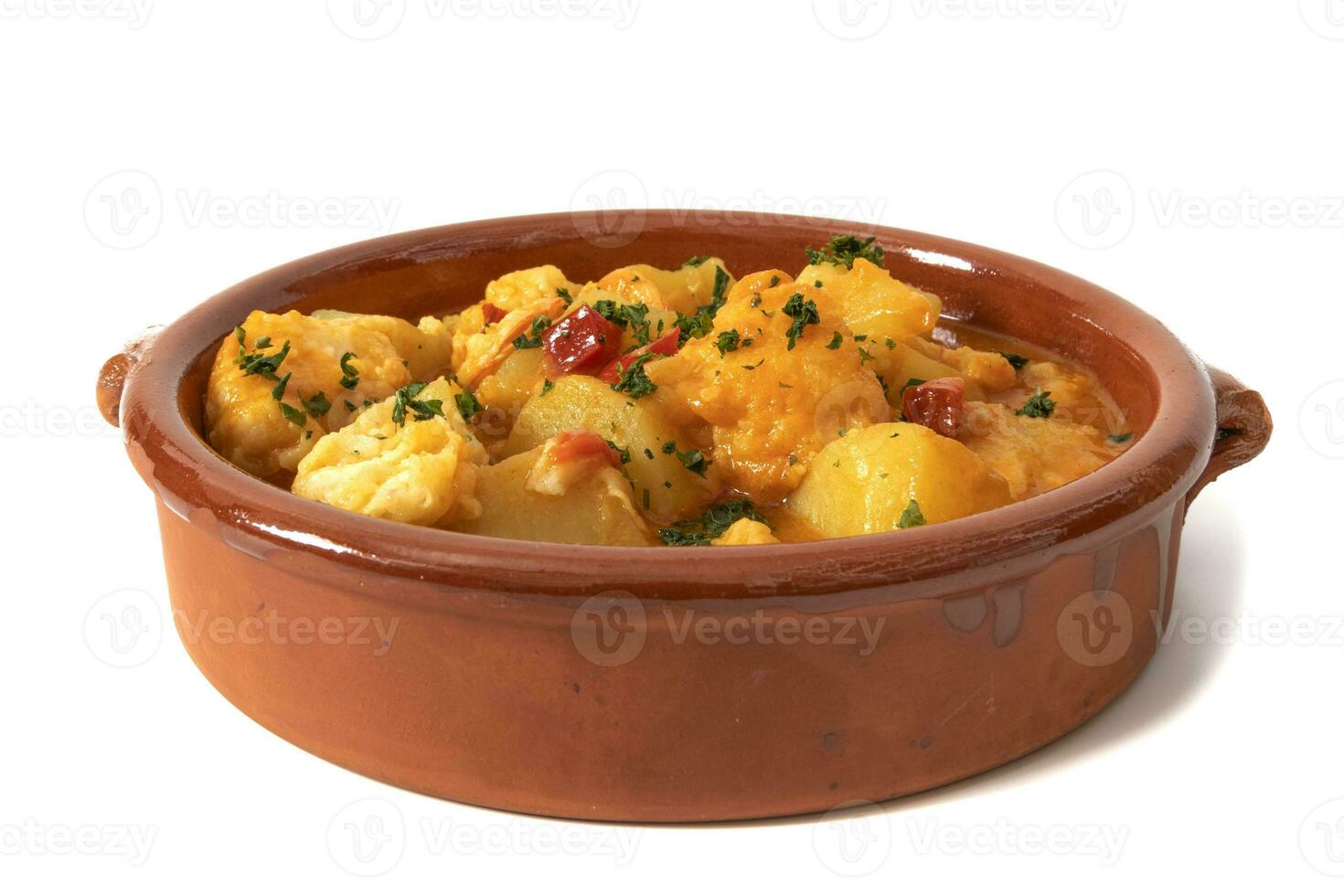 Potato stew with cod, served in a clay bowl. Isolated on white background. Spanish food concept. photo