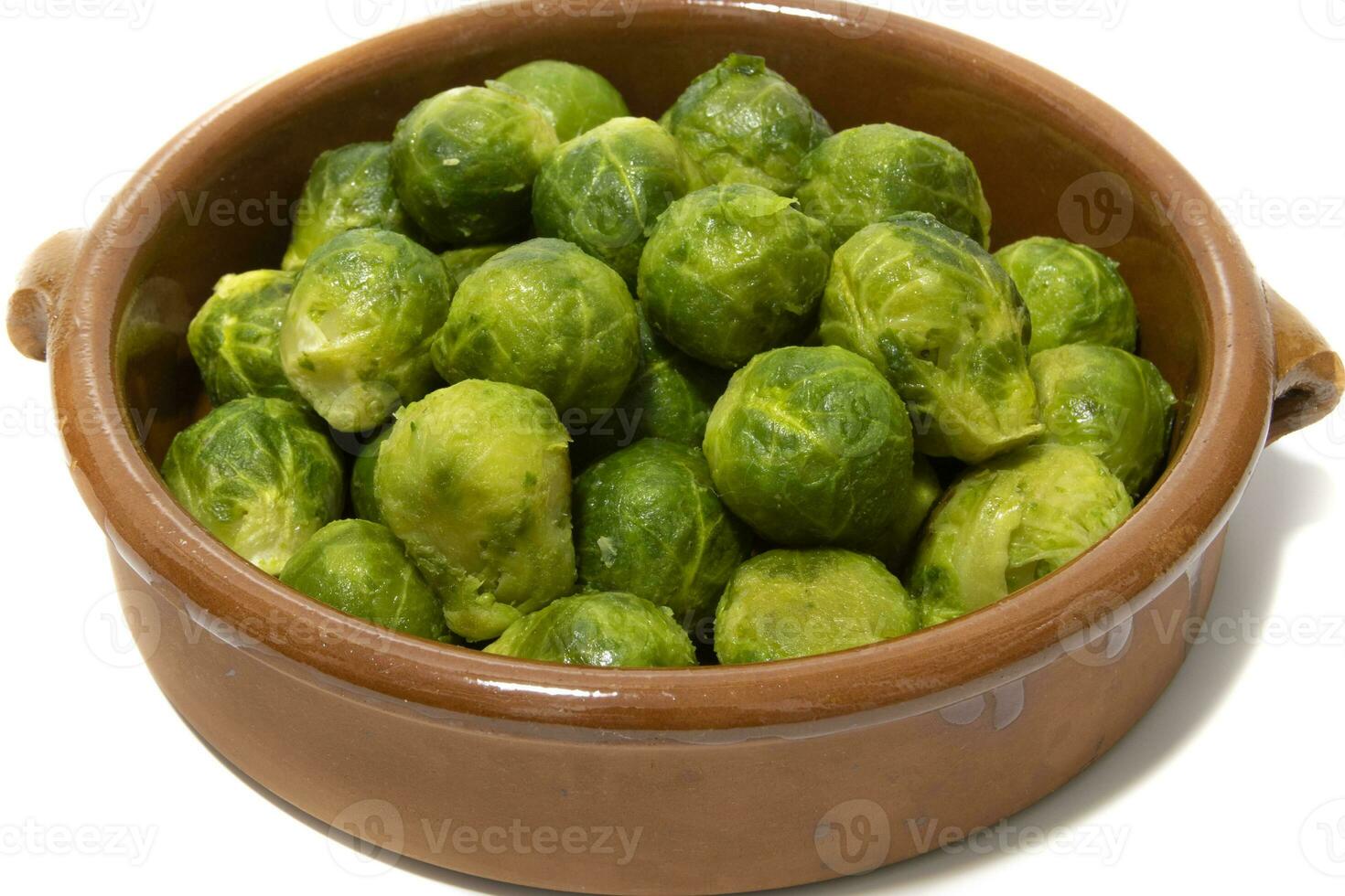 A pile of boiled brussels sprouts, served in a clay bowl. Isolated on a white background. Healthy food concept. photo