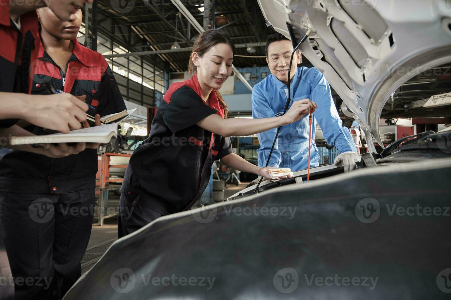 Asian male professional automotive supervisor advises and inspects a mechanic worker woman about liquid engine oil at car garage, service maintenance, and fix specialist occupations auto industry. photo