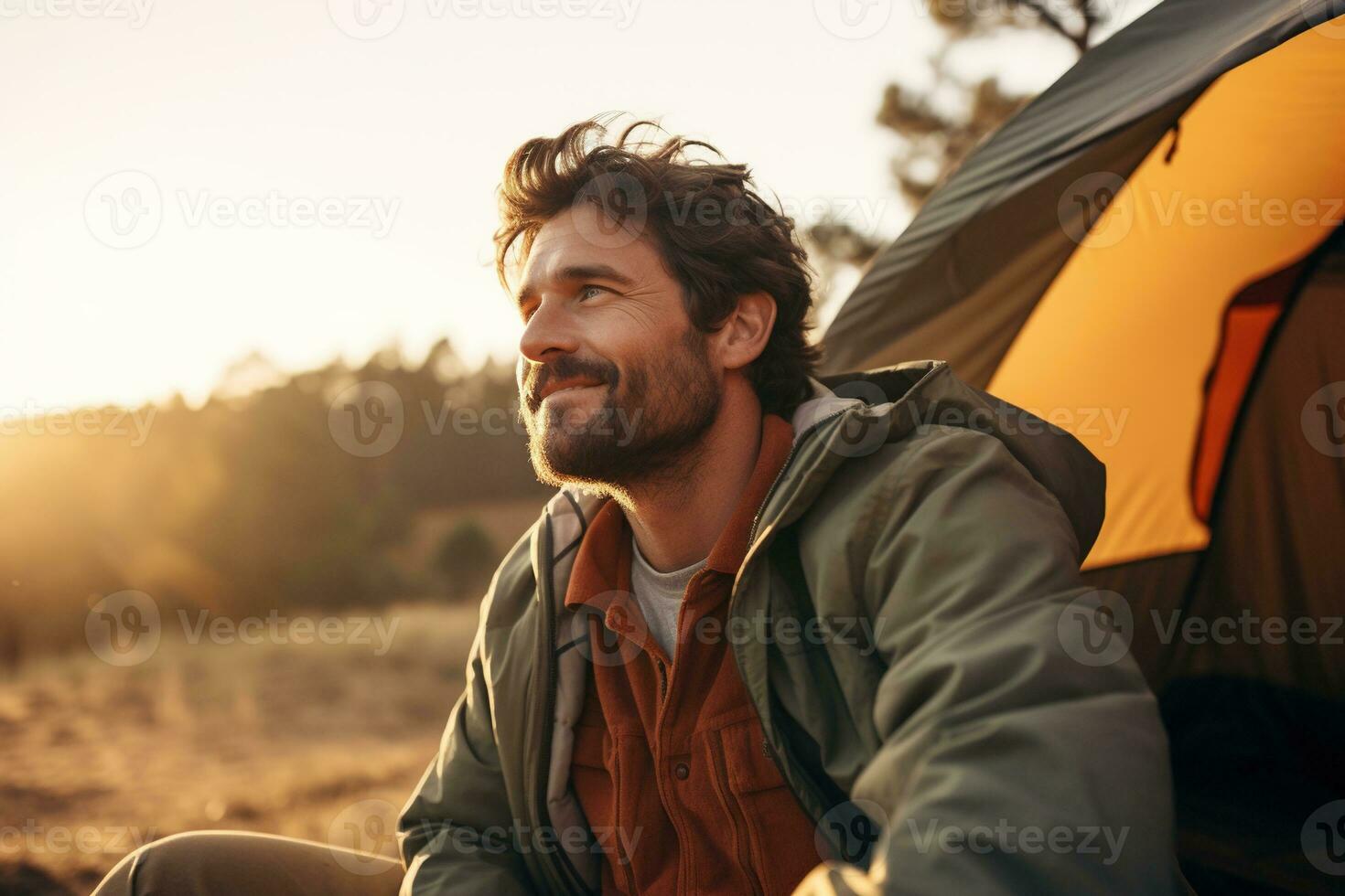 Portrait of man looking at camera while near camping tent at sunset AI generated photo