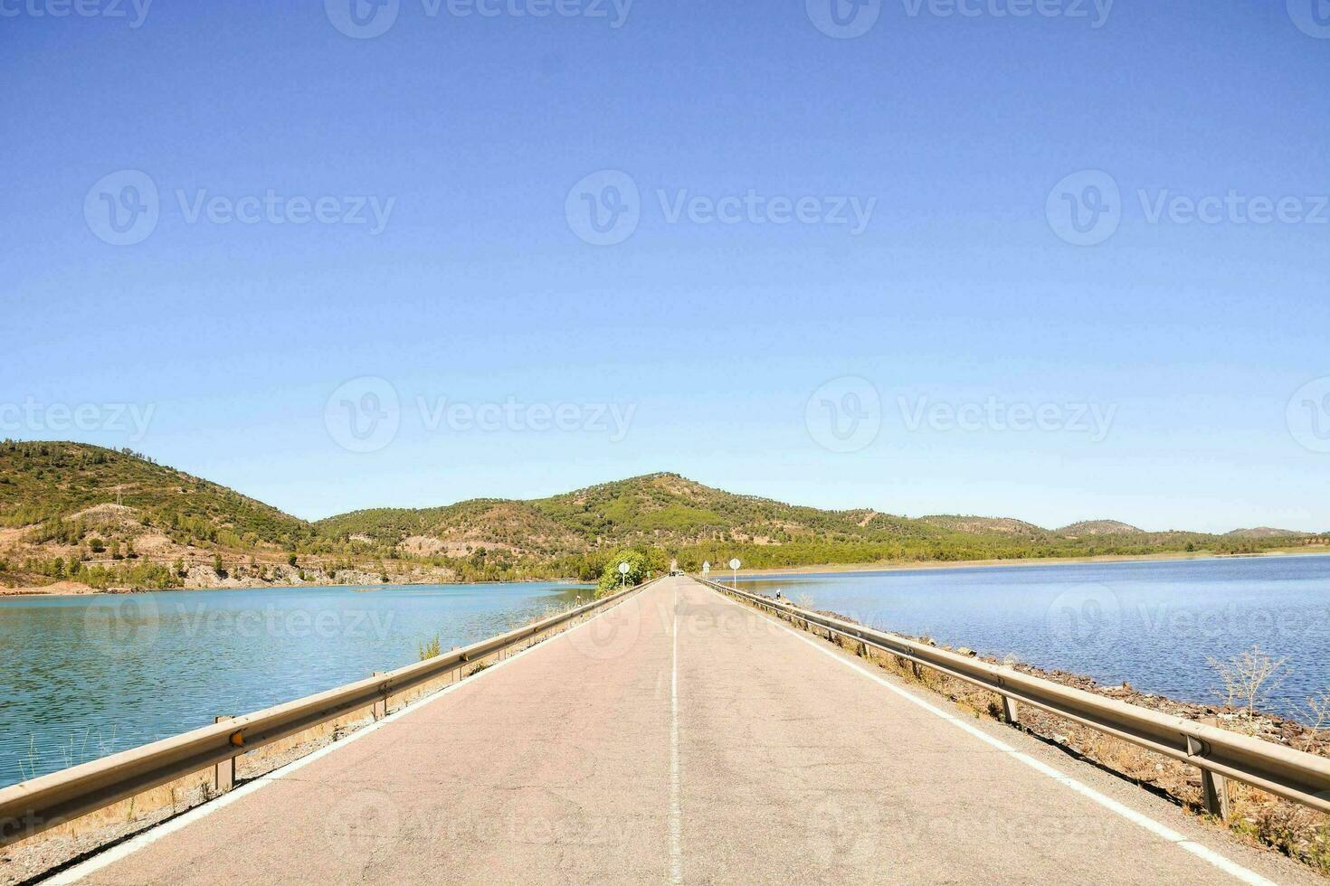 un largo puente terminado un lago con montañas en el antecedentes foto