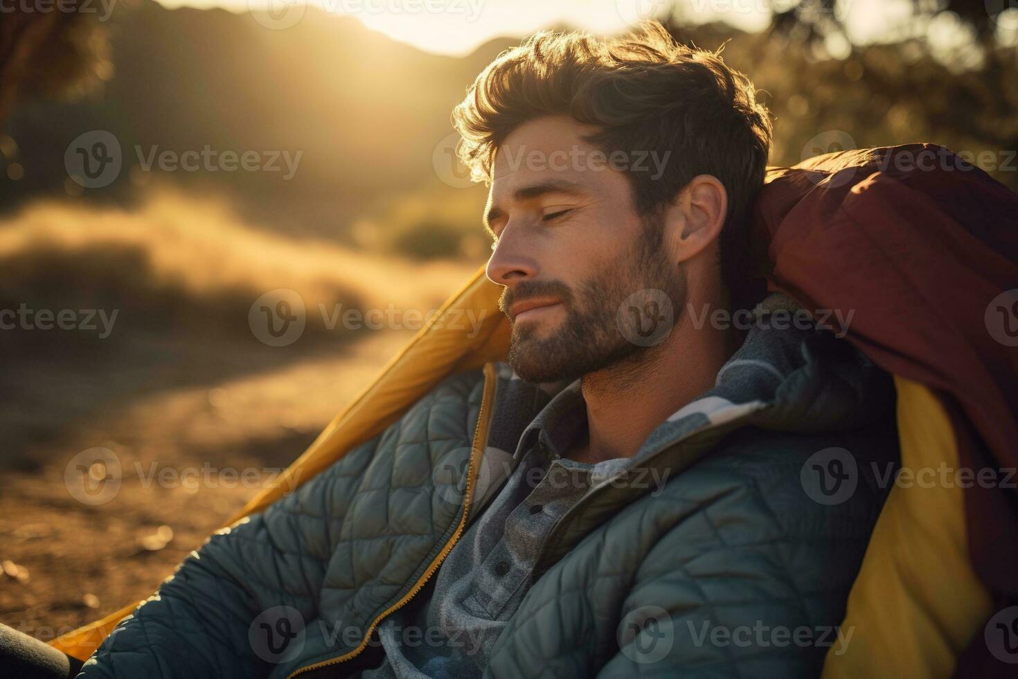 Portrait of man looking at camera while near camping tent at sunset AI generated photo