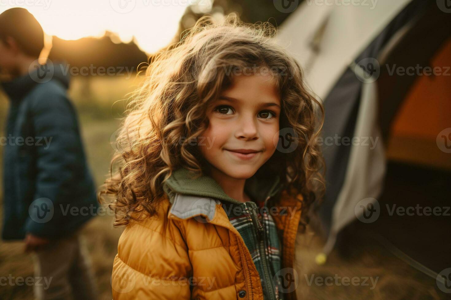 Portrait of cute little girl at camera while standing near camping tent at sunset AI generated photo