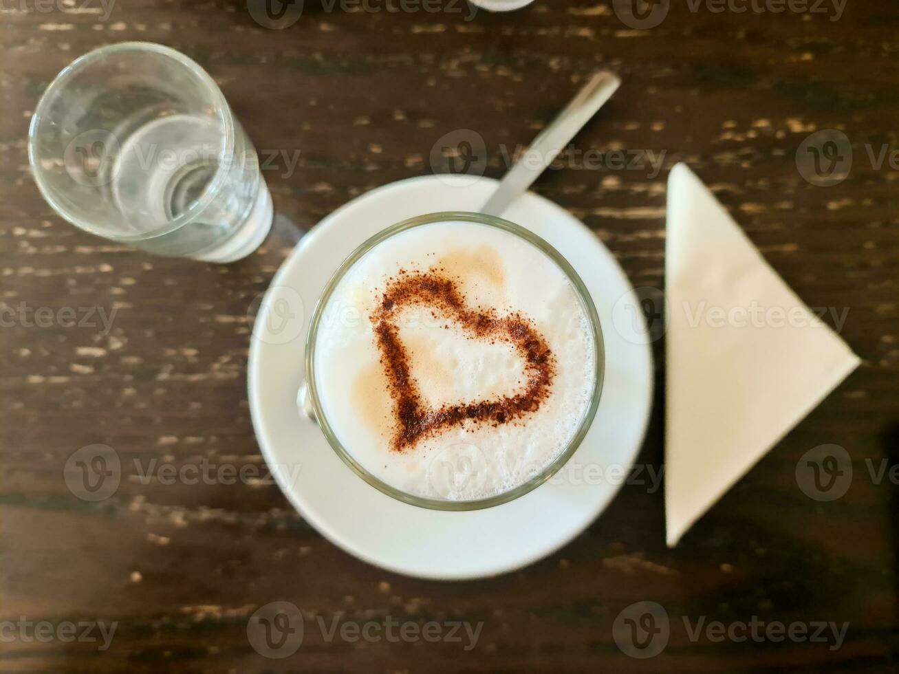 A tasty coffee with milk and a heart of chocolate on it photo