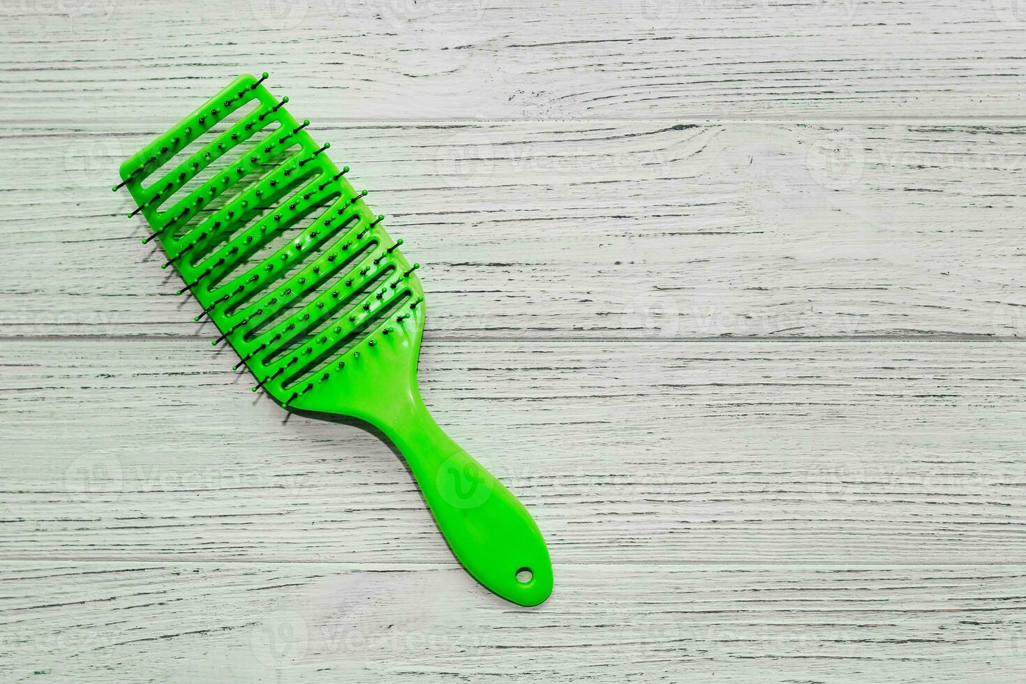 Massage light green hair brush on a wooden background. photo