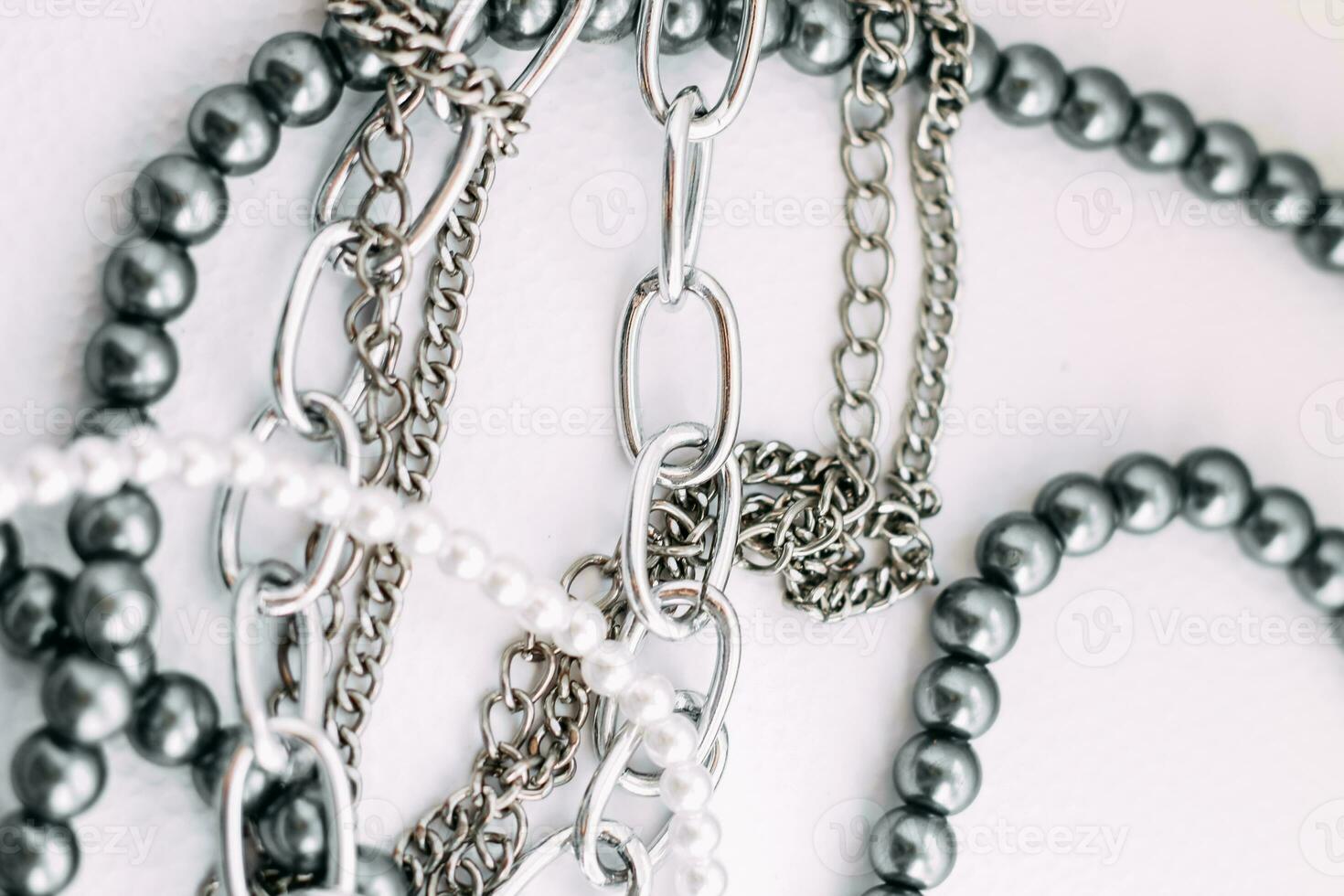 A necklace of gray beads with chain decorations on a white aesthetic background. photo