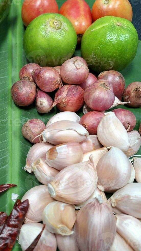 Photo of a pile of chili, lemon, shallot Garlic placed on a banana leaf