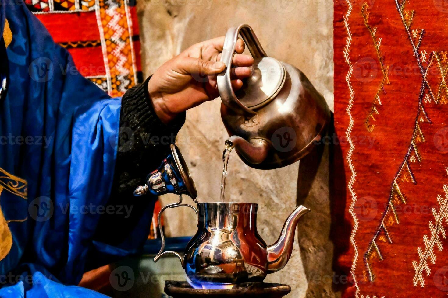 a man in blue robes pouring tea photo