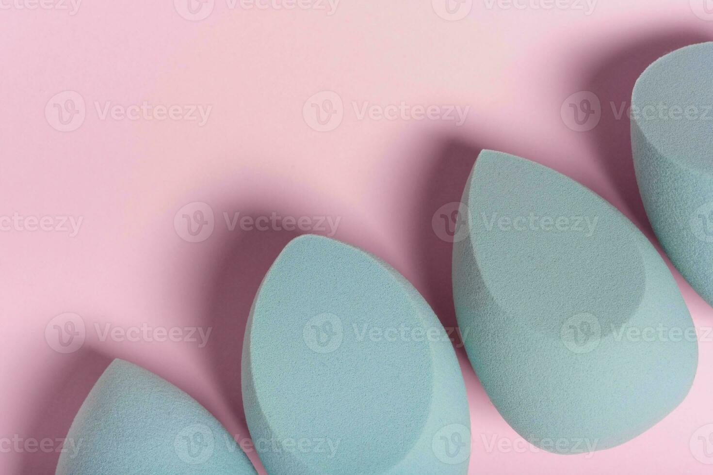 Blue cosmetic makeup set sponge on a minimal pink background. Tool for applying foundation cream photo