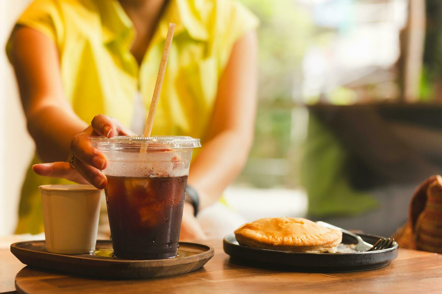 Woman hand reaching glass of coffee on table. photo