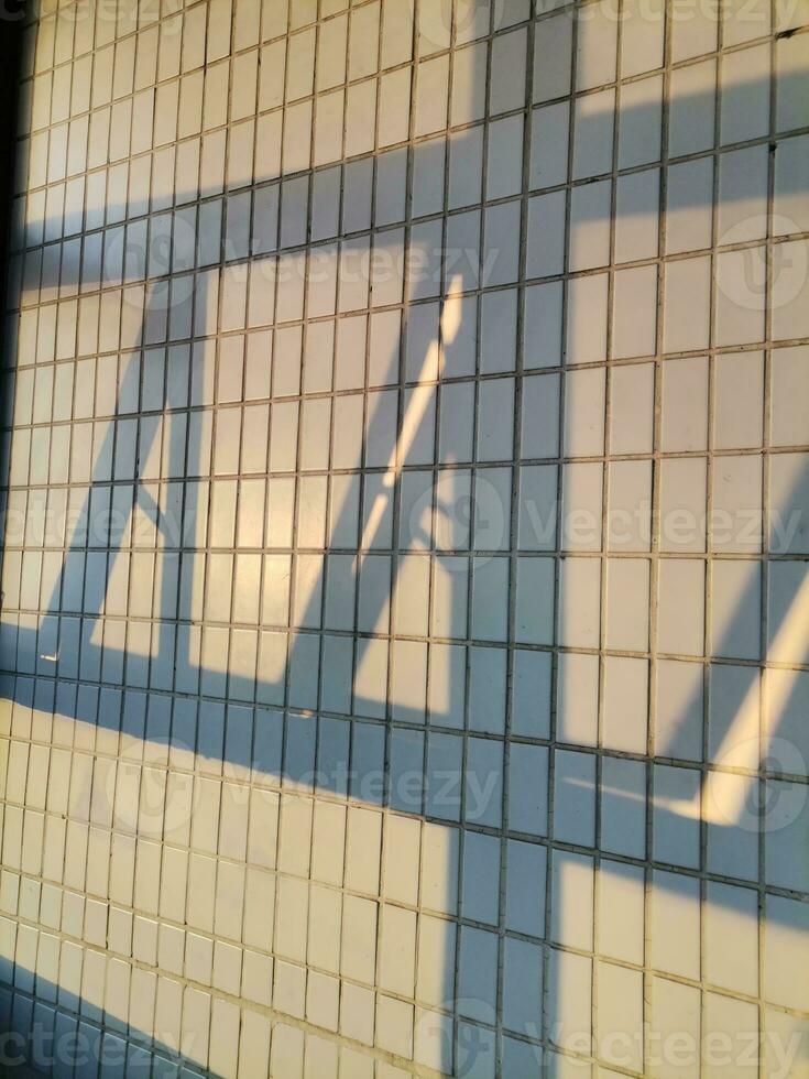 The evening sunlight shone through the window and cast shadows on the white tiled walls. photo