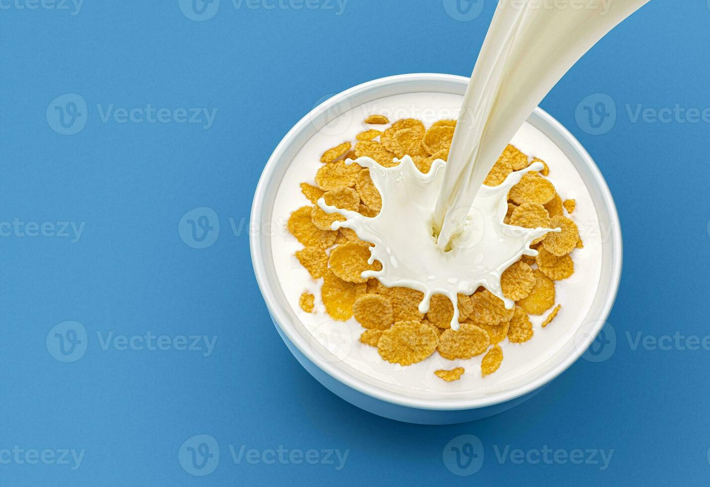 Corn flakes with pouring milk on blue background, top view photo