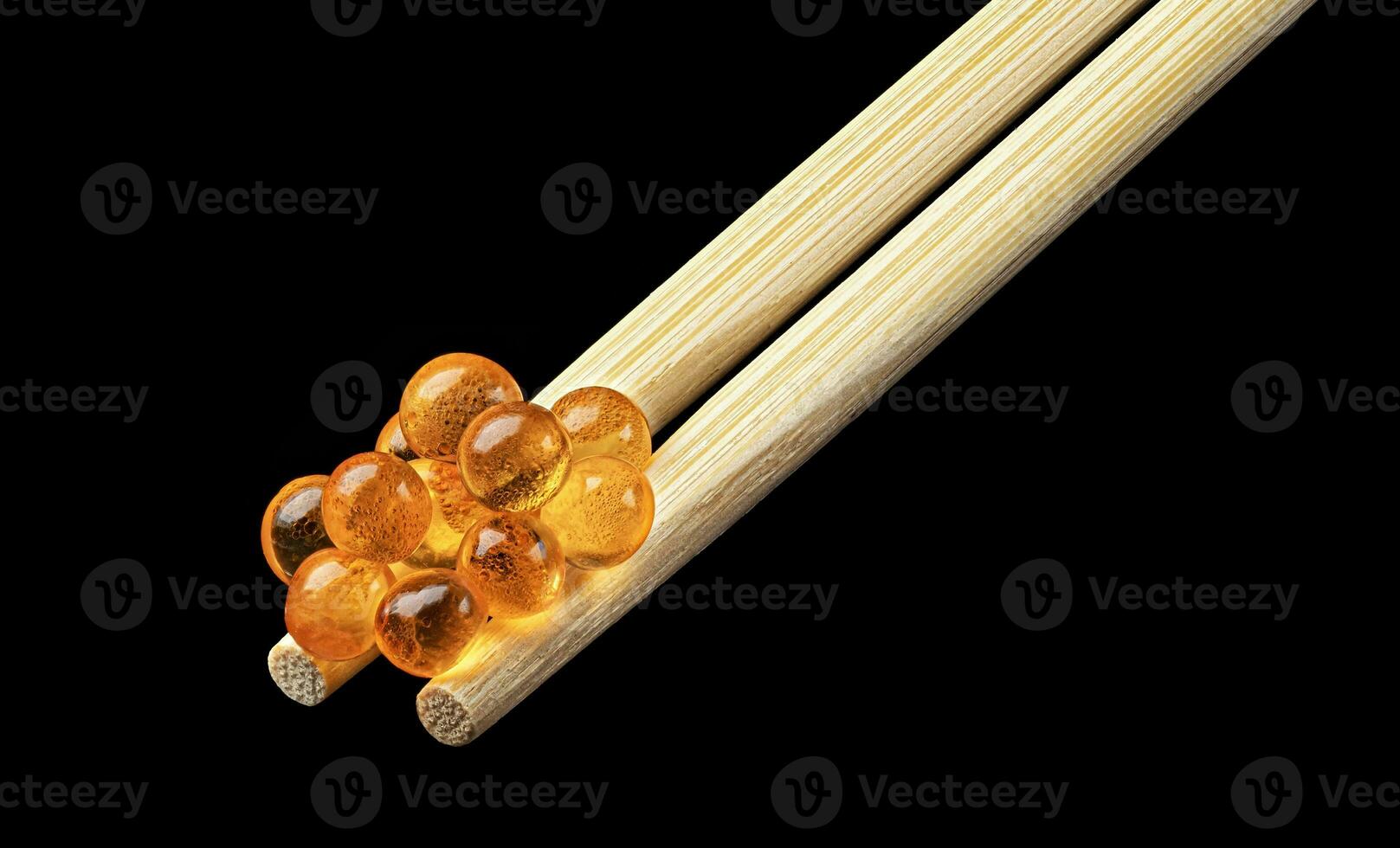 Red caviar on chopsticks for sushi isolated on black background photo