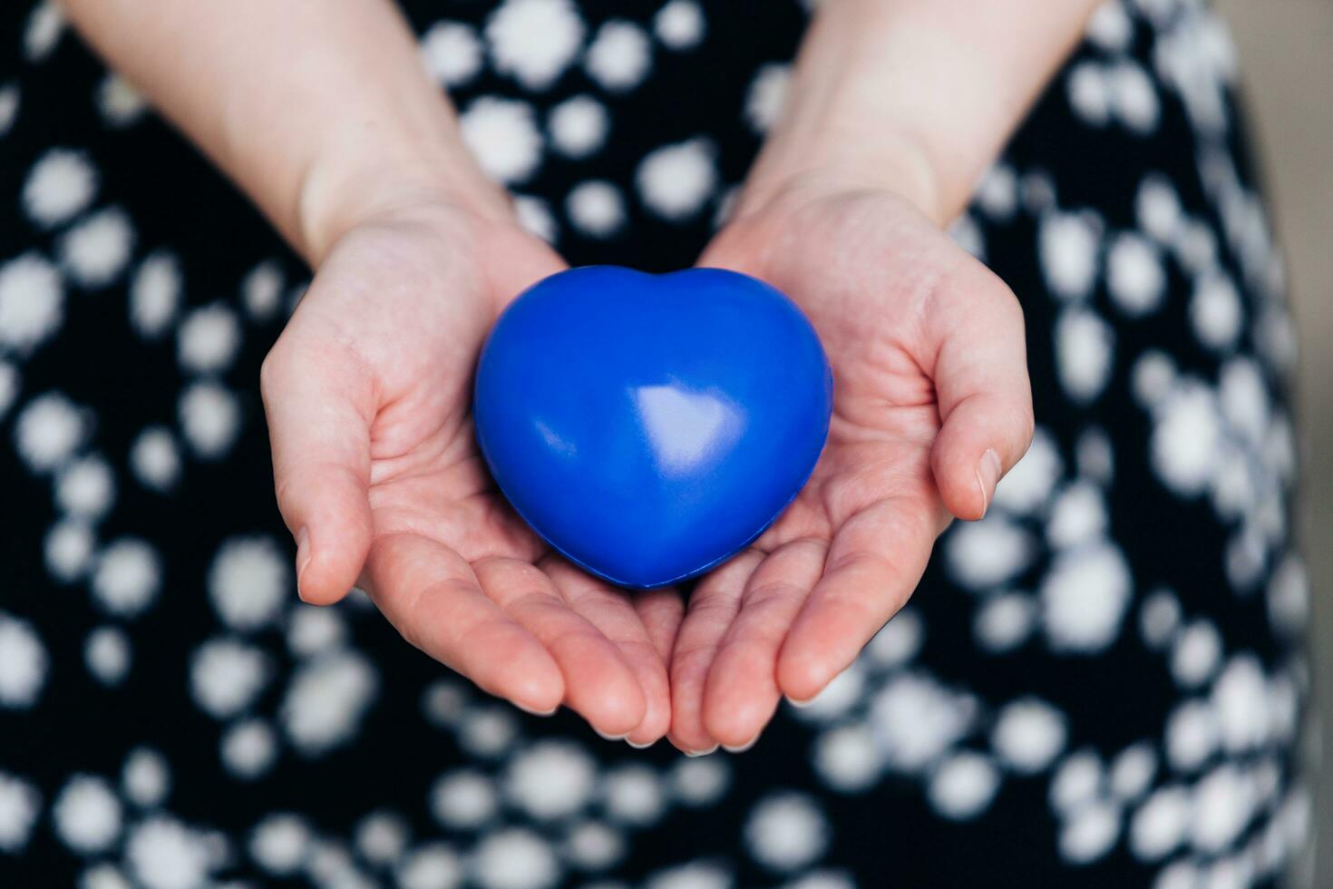Blue heart in the hands of a woman in a polka dot dress photo