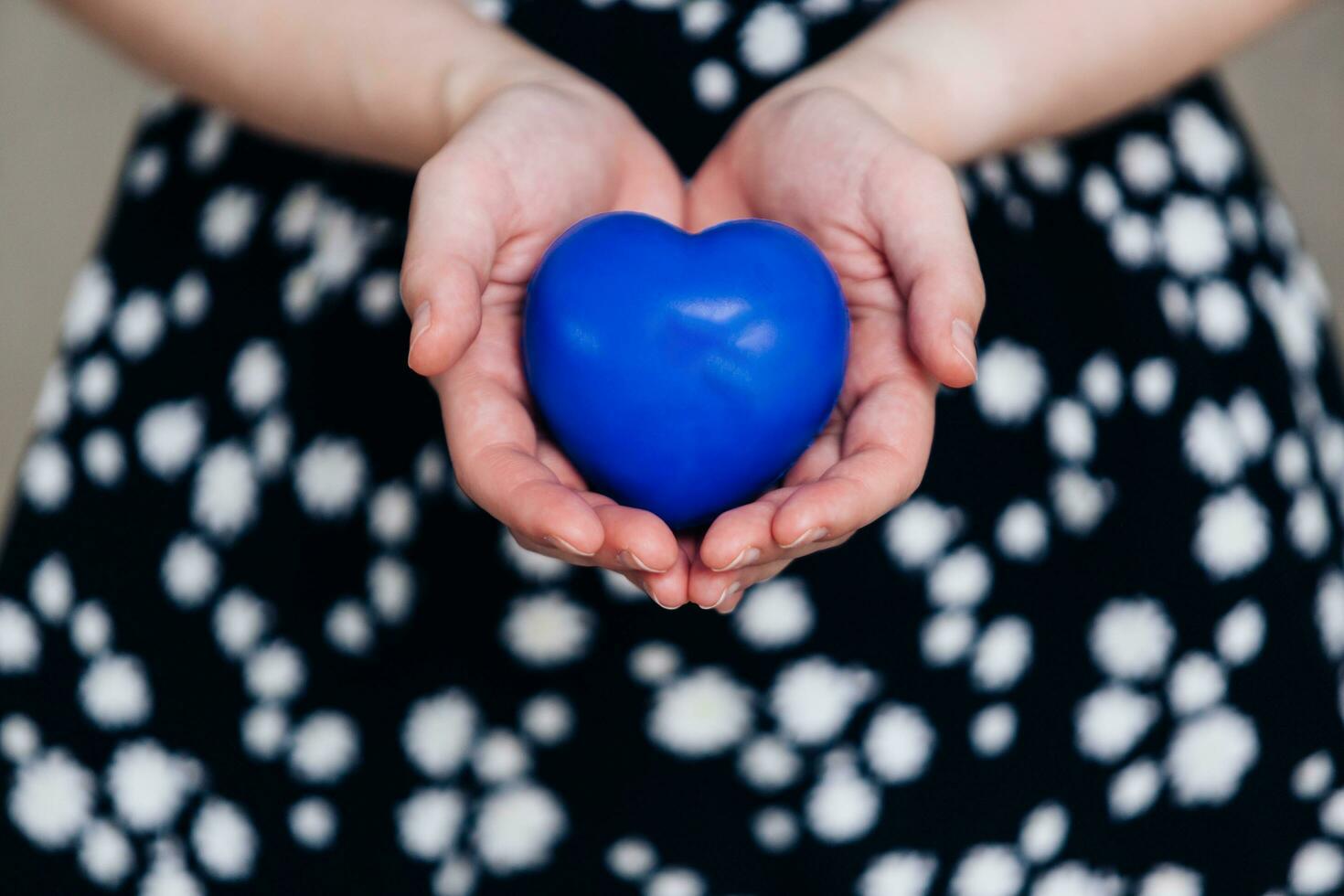 Blue heart in the hands of a woman in a polka dot dress photo