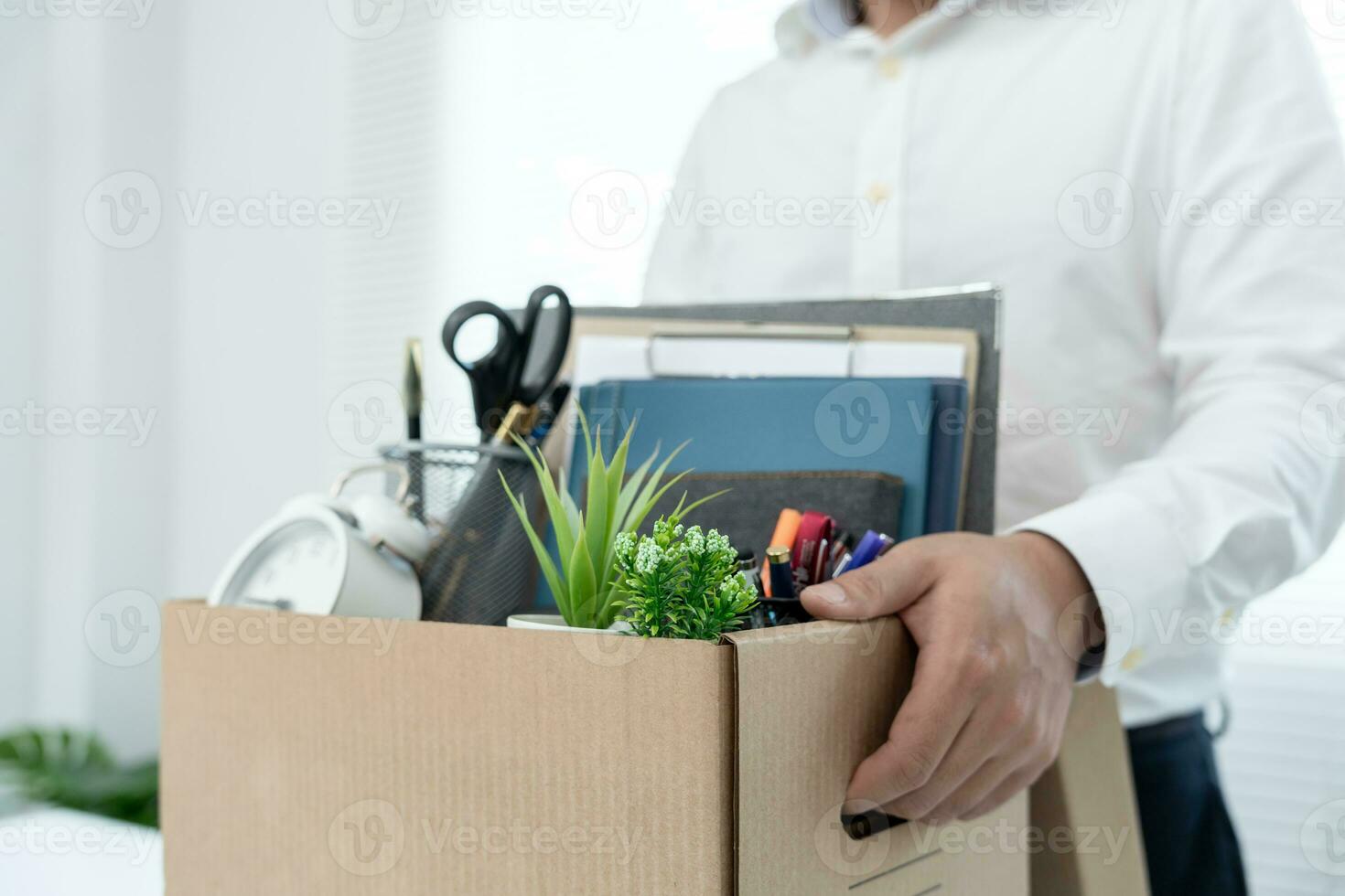 Stressful businessmen will resign from the company. He is lifting a brown paper box that holds personal items. resignation, job placement and vacancies concept. photo