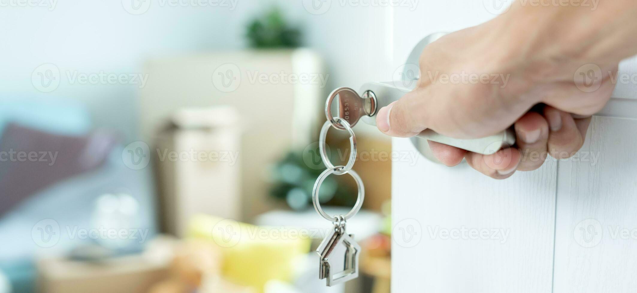 Moving house, relocation. The key was inserted into the door of the new house, inside the room was a cardboard box containing personal belongings and furniture. move in the apartment, banner photo