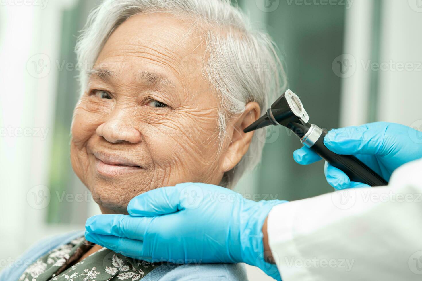 Audiologist or ENT doctor use otoscope checking ear of asian senior woman patient treating hearing loss problem. photo