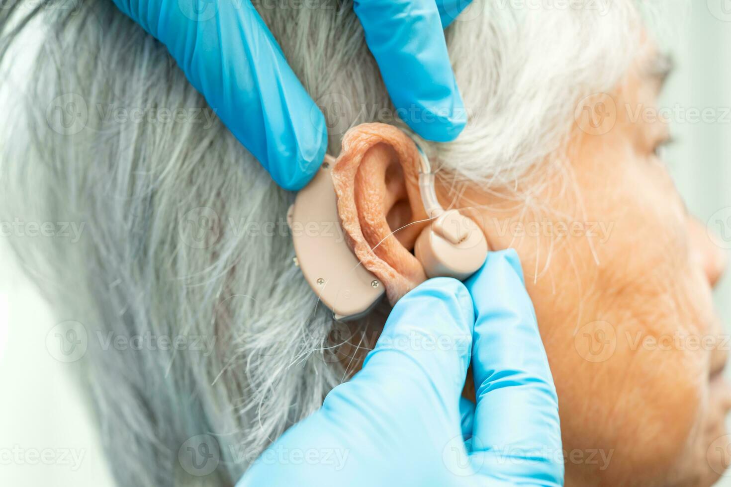 Asian senior woman patient wearing a hearing aid for treating hearing loss problem. photo