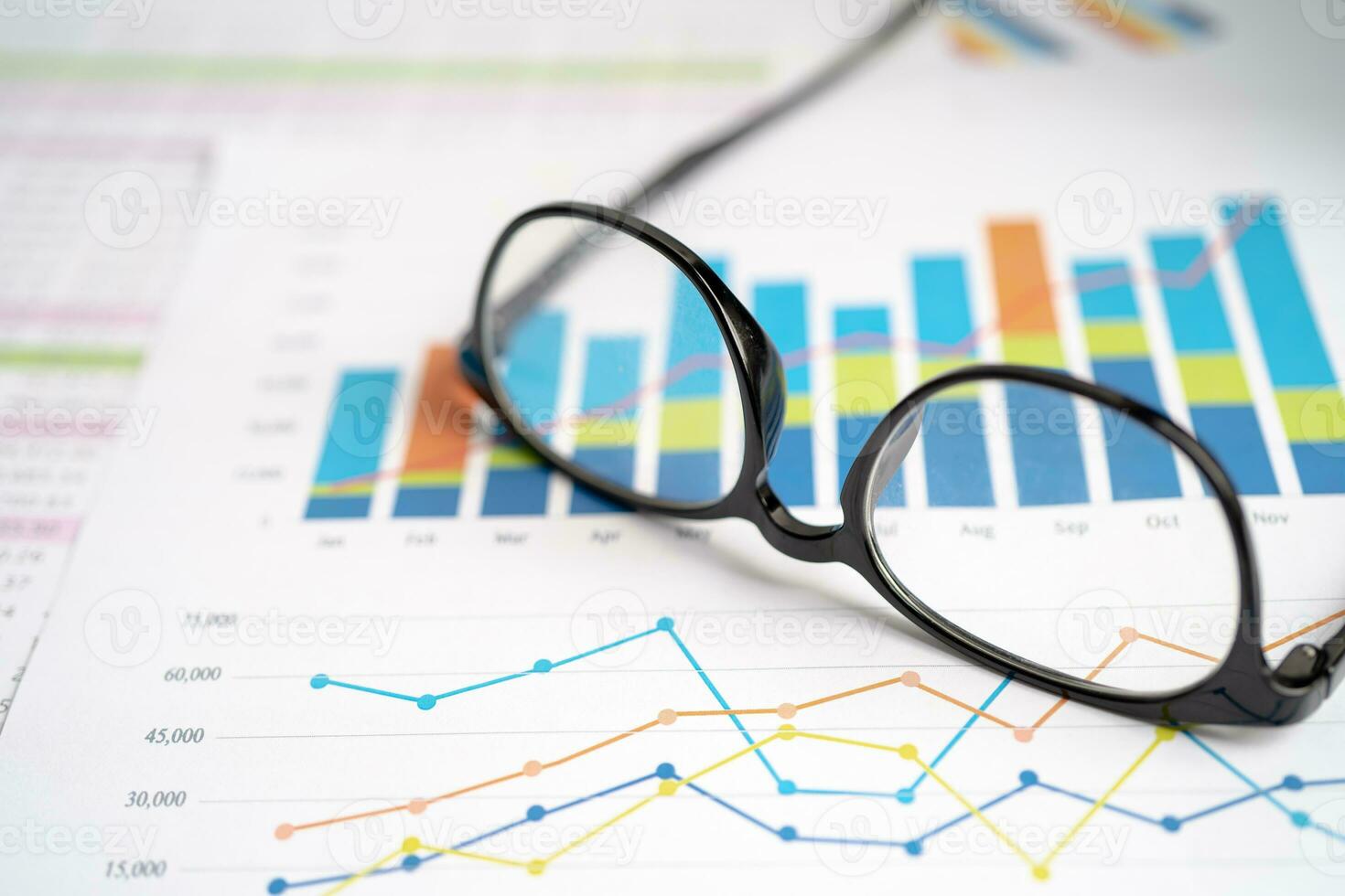 Eyeglass with calculator on chart graph paper. Finance, account, statistic, investment data economy, stock exchange business. photo