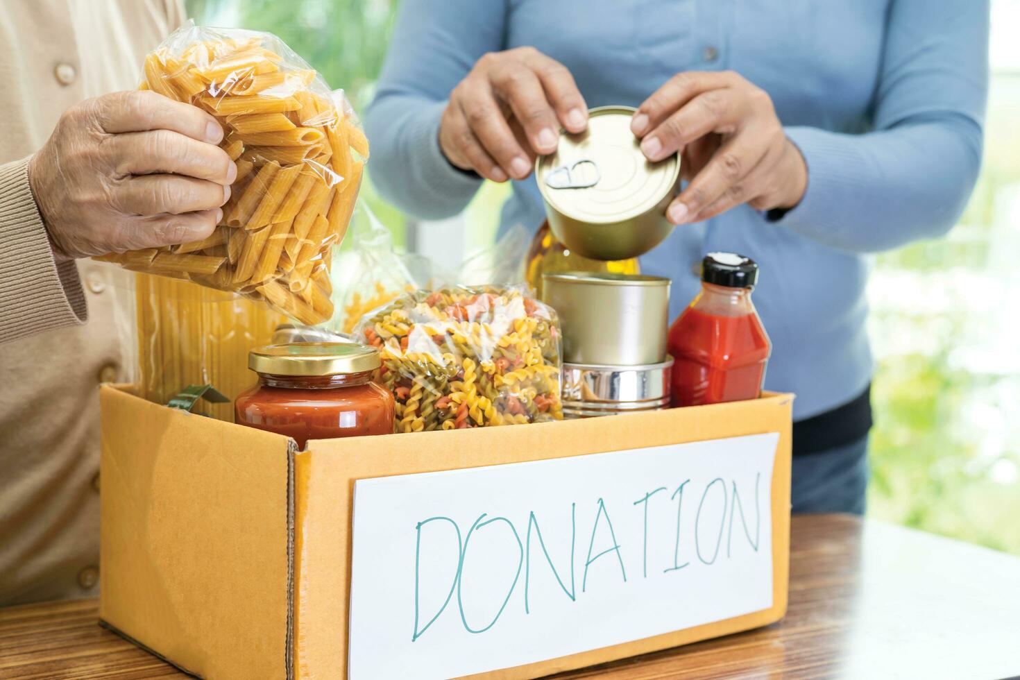 Volunteers putting various dry food in donation box for help people. photo