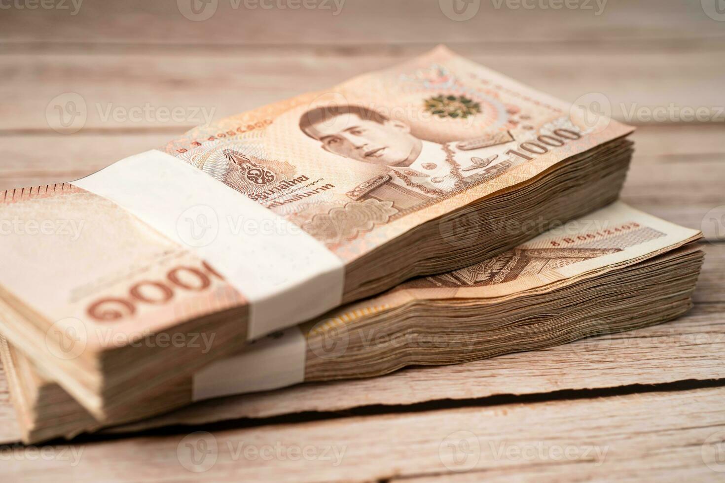 Stack of Thai baht banknotes on wooden background, business saving finance investment concept. photo