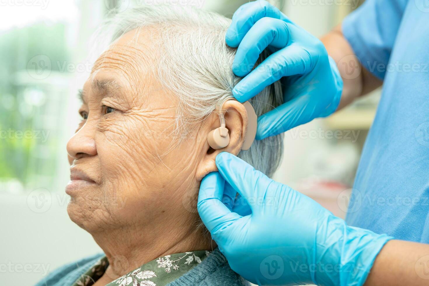 Audiologist or ENT doctor use otoscope checking ear of asian senior woman patient treating hearing loss problem. photo