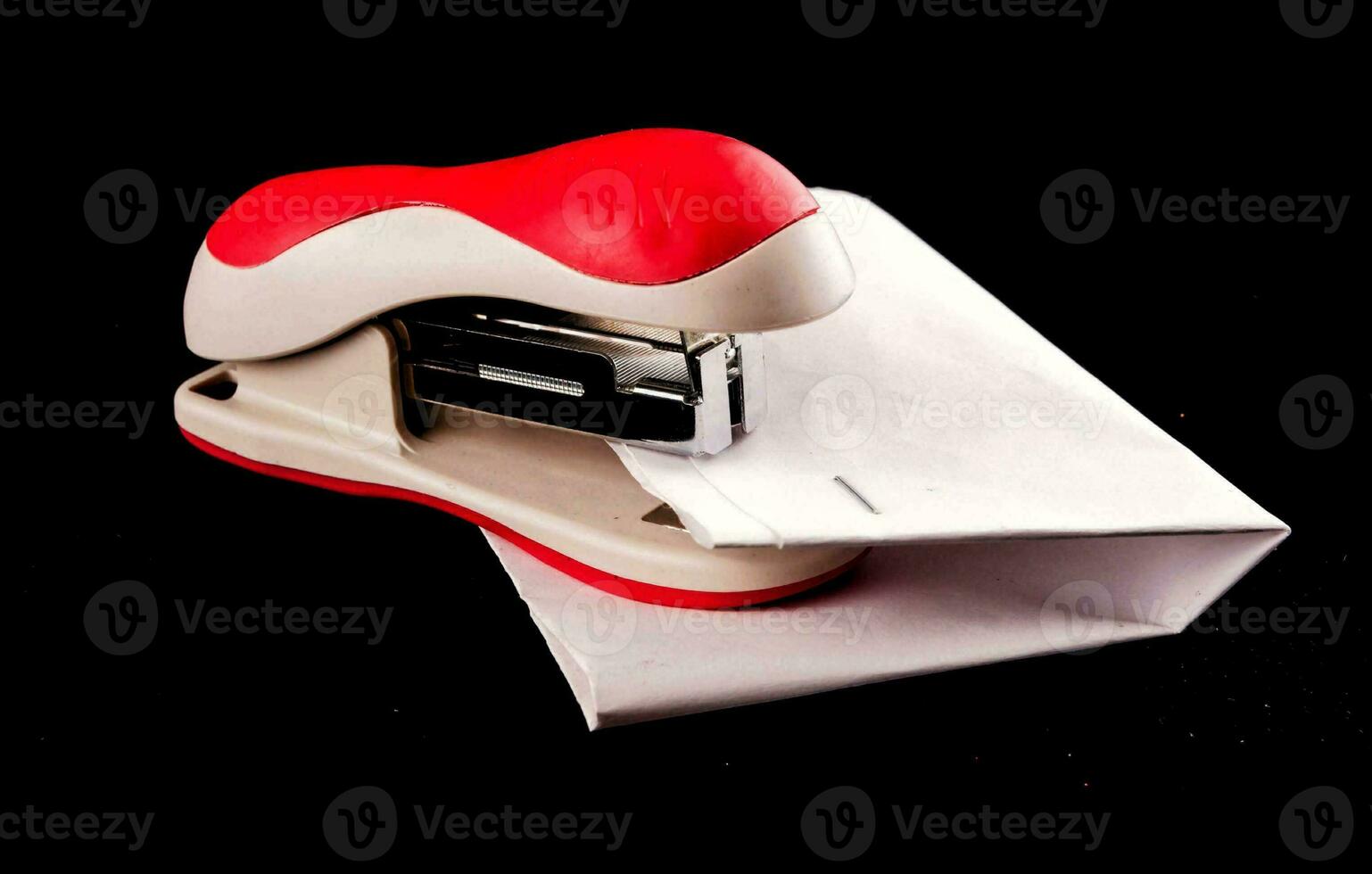 a red stapler with a white envelope on a black background photo