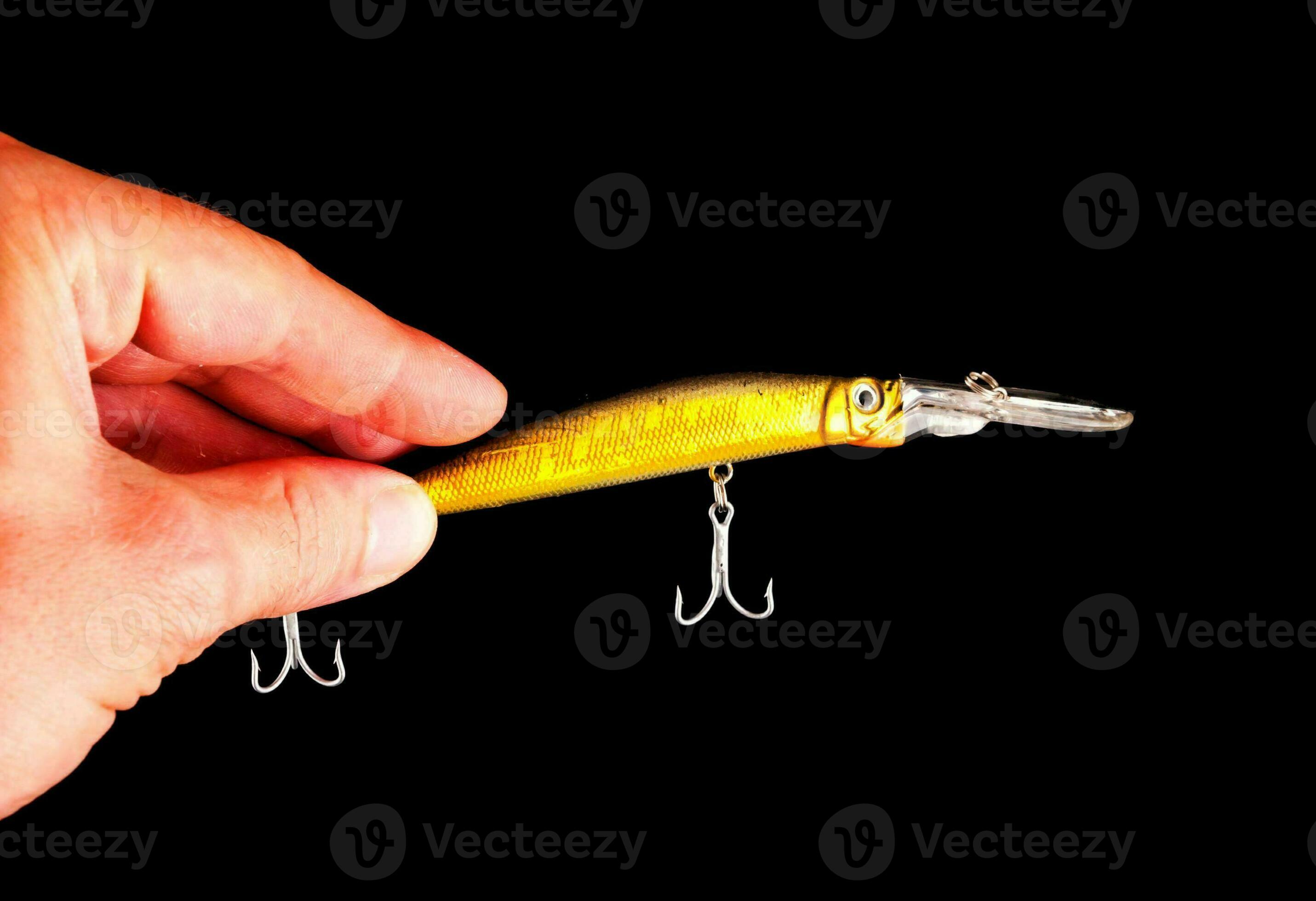 a person holding a fishing lure on a black background 33306246
