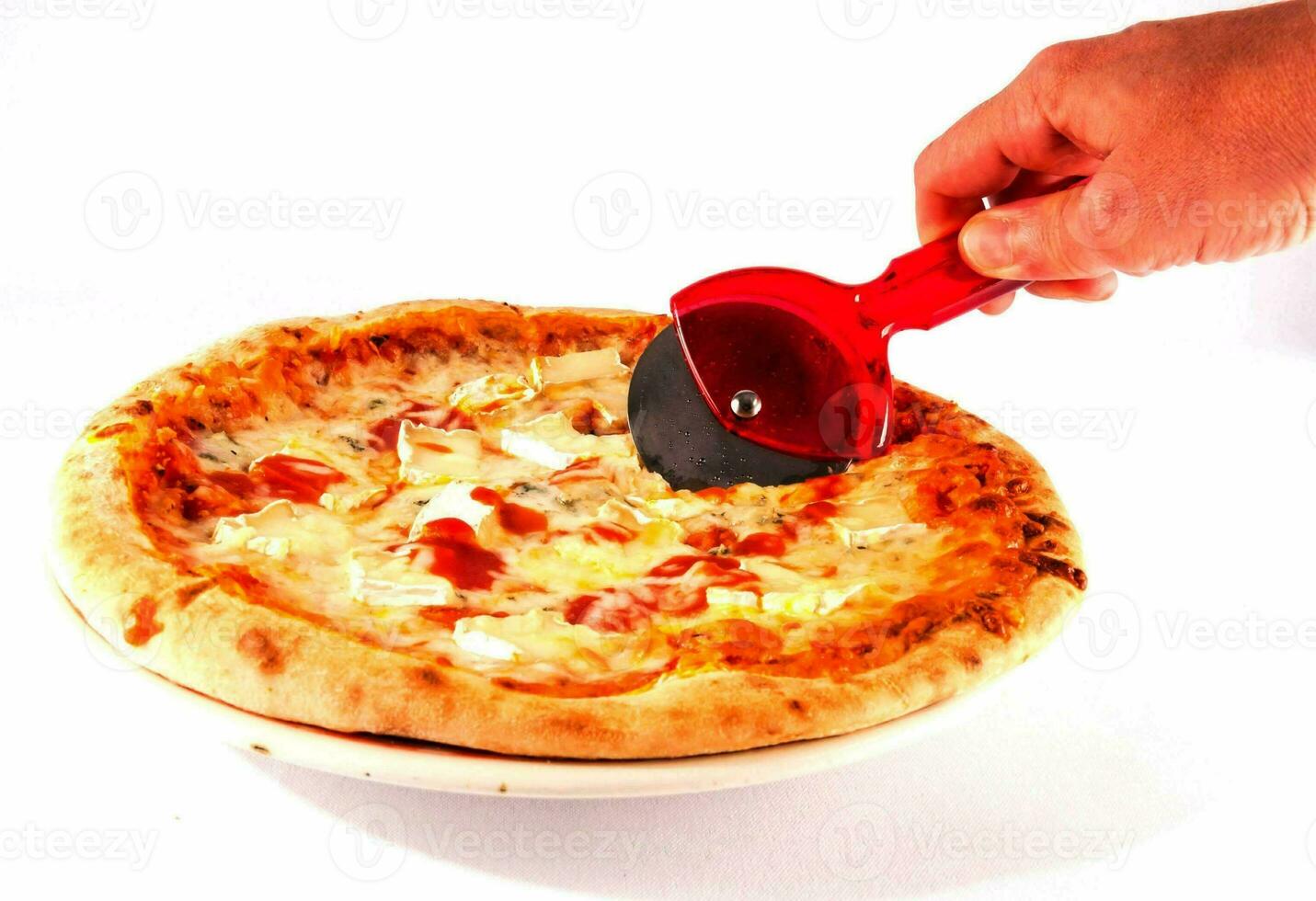 a person is using a pizza cutter to cut a pizza photo