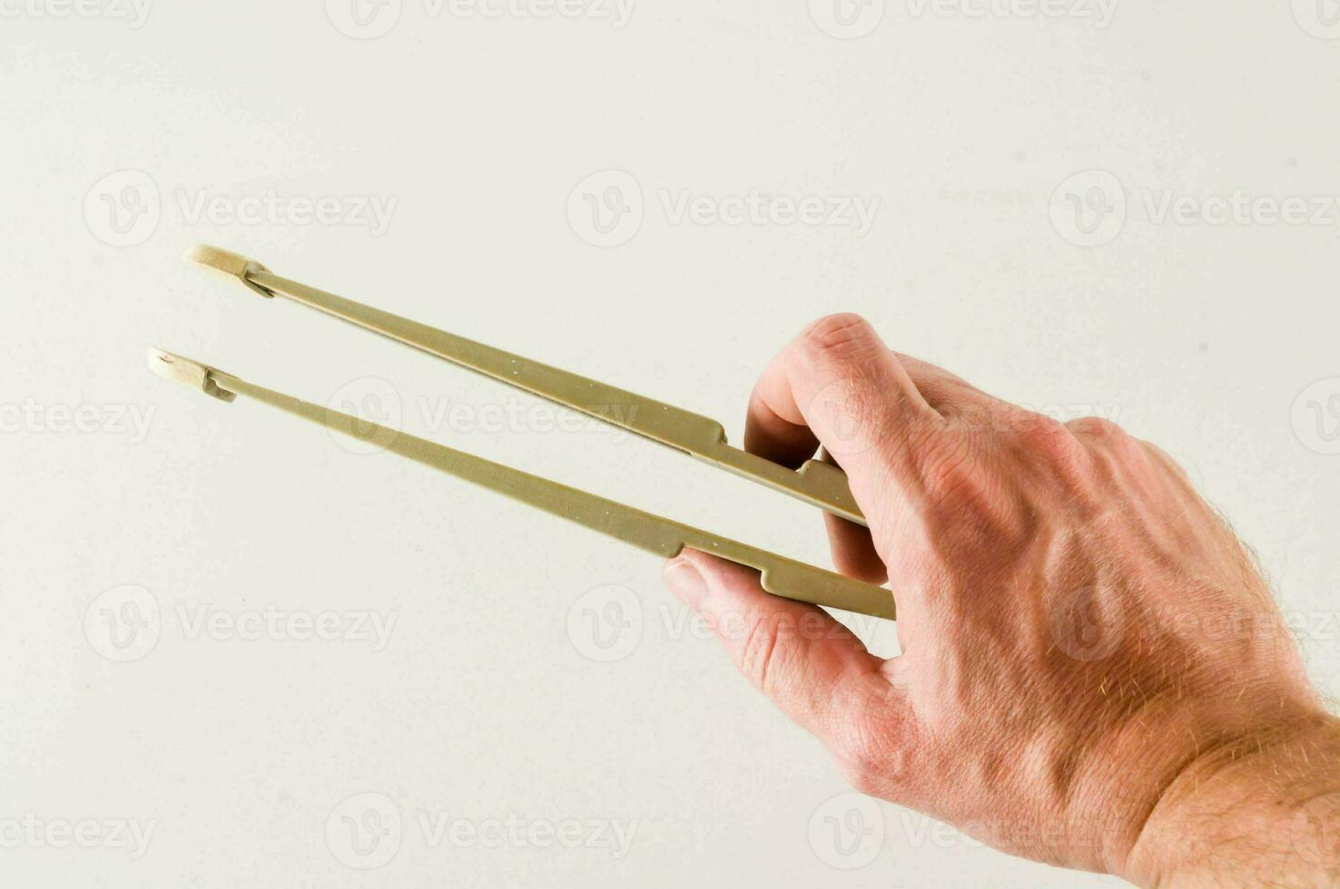 a person holding a pair of metal tongs photo