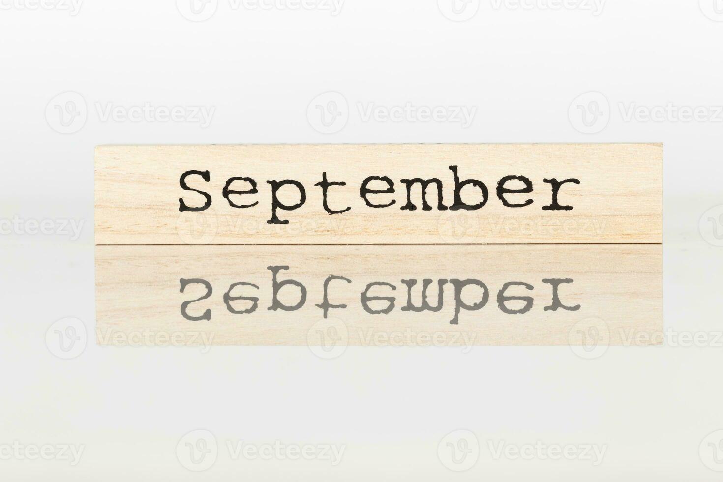 wooden cube with the inscription September on a white background photo