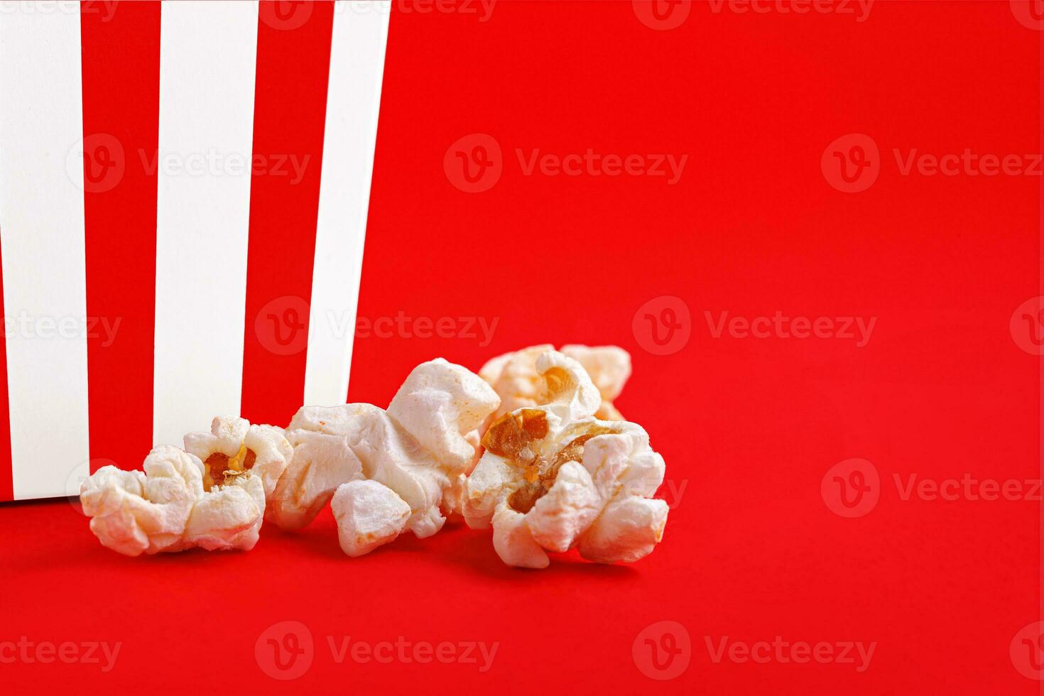 Glass with popcorn on a red background photo