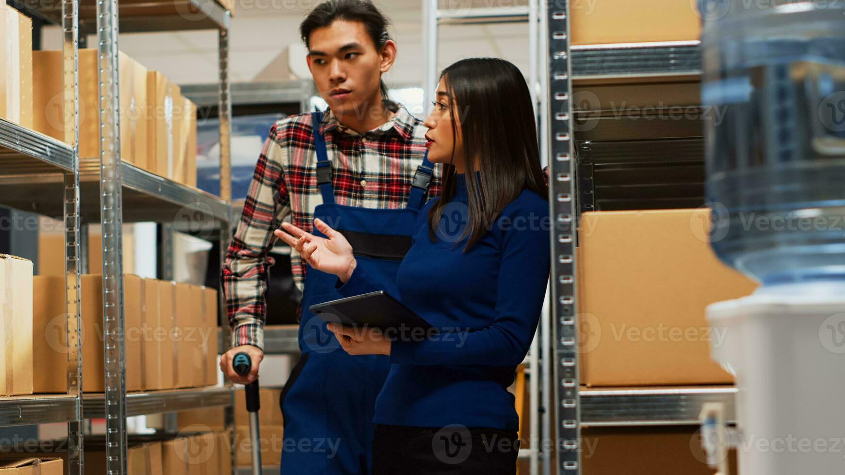 Man walking with crutches talking to business owner, using tablet to do products inventory in warehouse space. Employee talking to woman about merchandise, physical problem. Handheld shot. photo