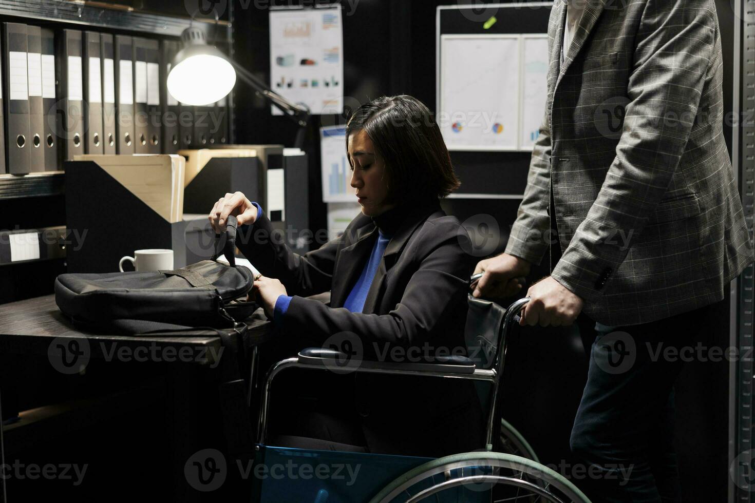 Management executive asian businesswoman with disability in wheelchair and coworker starting job shift. Accountants surrounded by bureaucratic data paperwork in depository cabinet office photo