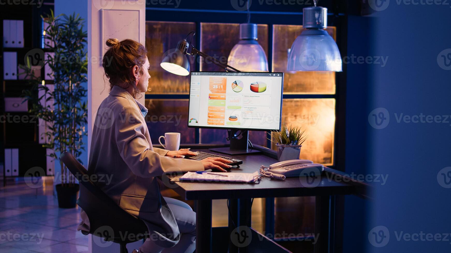 Corporate worker typing data on online report and planning financial development, working on business growth at night. Female manager analyzing graphs analytics at desk. Handheld shot. photo