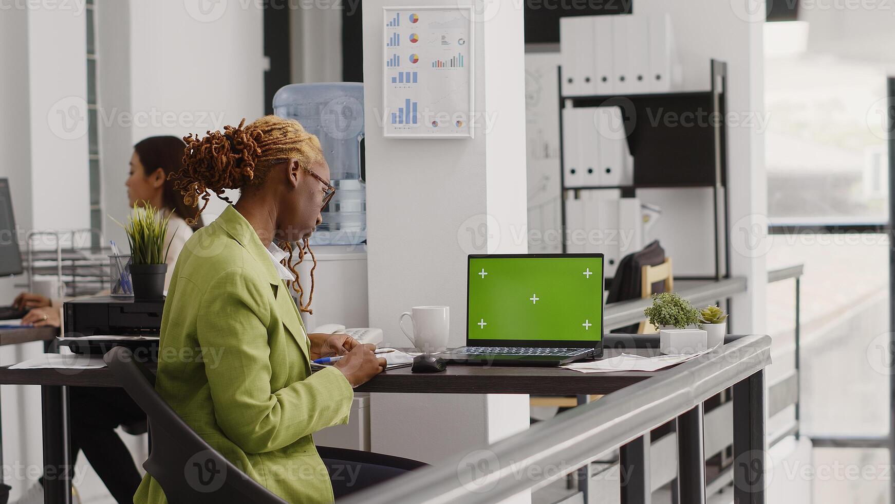 Young manager analyzing greenscreen template on laptop, using pc with chroma key display in office. Business entrepreneur looking at isolated blank mockup in agency coworking space. photo