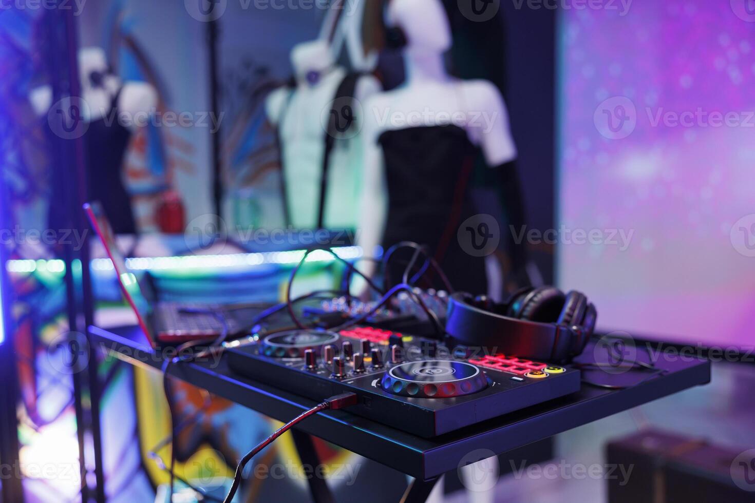 Dj controller for electronic music concert at dark club stage with spotlight glow. Musician console panel for sound mixing and headphones for live performance in nightclub close up photo