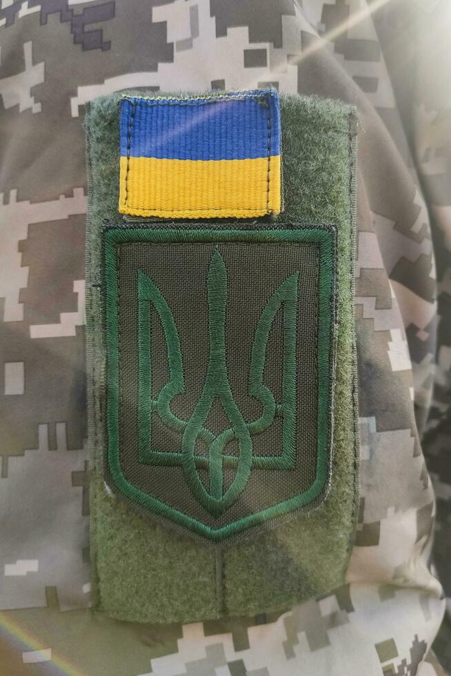 Close-up texture pixel camouflage military uniform of the Armed Forces, chevron trident and flag of Ukraine photo