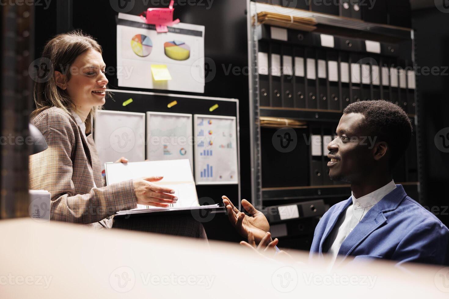 Team discussing bookkeeping report, working late at night at bureaucracy record in storage room. Diverse depository workers analyzing administrative documents, discovering accountancy files photo